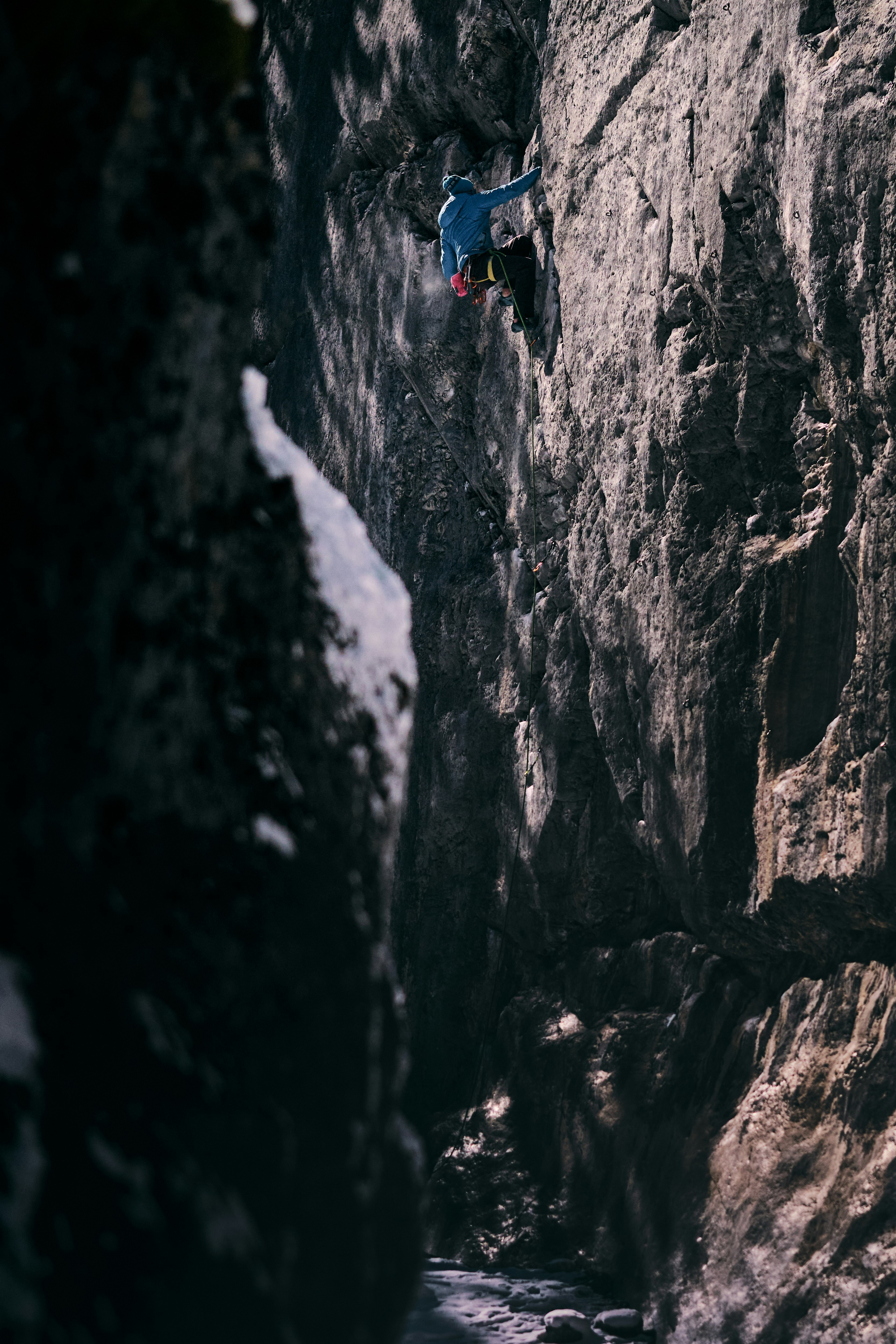 person in blue jacket climbing on rocky mountain during daytime